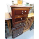 A pair of dark wood three drawer beside cabinets