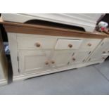 A cream painted oak sideboard with three doors and three drawers under