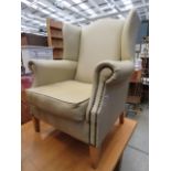 A cream leather effect wingback armchair