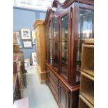 A dark wood glazed wall unit with dresser base under