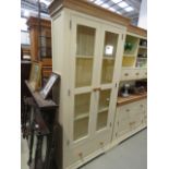 A cream painted and glazed double door bookcase, with drawer under