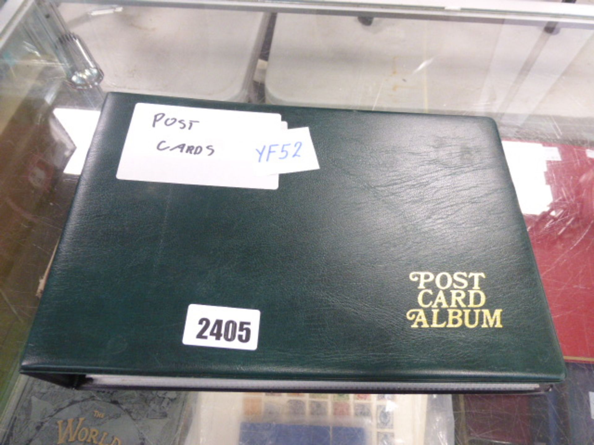 Green album binder containing various vintage and collectible postcards
