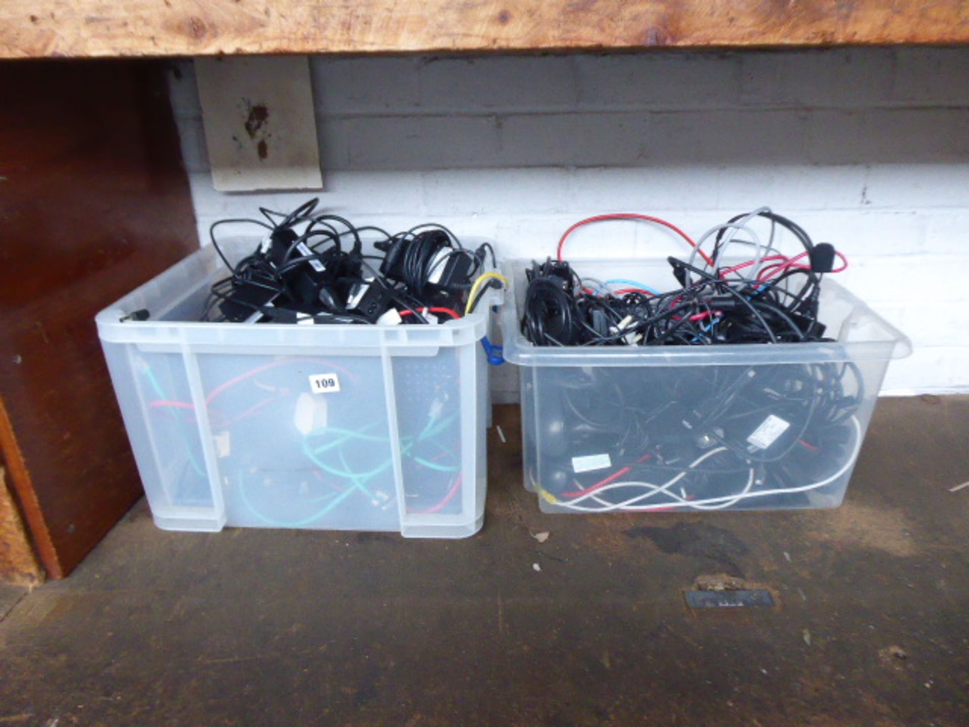 2 plastic boxes containing assorted power supply units and cabling for IT