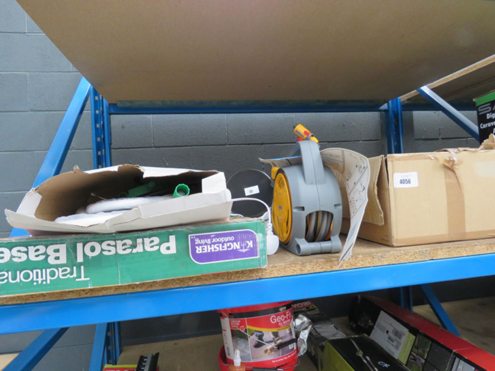 Half shelf containing outdoor lights, small hose reel, parasol base and a light