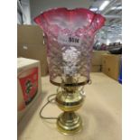 A brass finished table lamp with cranberry glass shade