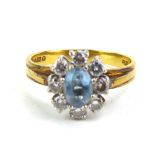 An 18ct yellow gold cluster ring set oval aquamarine and eight brilliant cut diamonds, London 1987,