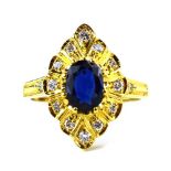 An 18ct yellow gold ring set oval sapphire and twelve small diamonds in a marquise shaped setting,