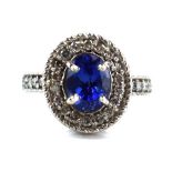 A 14ct white gold ring set oval cut tanzanite within a border of small diamonds,
