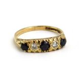 A 9ct yellow gold ring set three graduated dark sapphires interspersed with two small diamonds in a