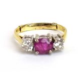 A yellow metal ring set oval ruby and two brilliant cut diamonds in a inline setting,