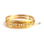 An early 20th century 9ct yellow gold hinged bracelet set four graduated opals interspersed with