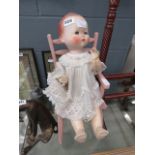 A child's doll in a pink painted chair