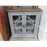 A grey painted glazed double door storage cabinet