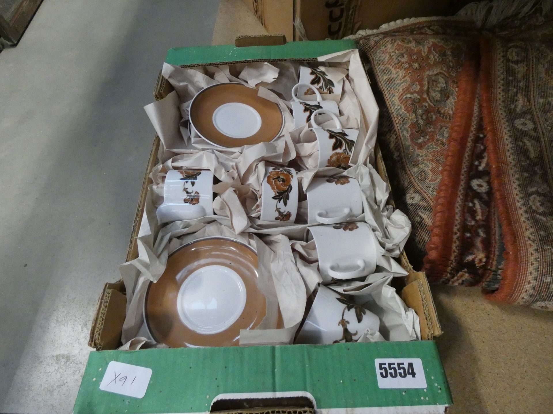 A box containing Susie Cooper floral and leaf pattern cups & saucers