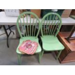 A pair of green painted stick back chairs