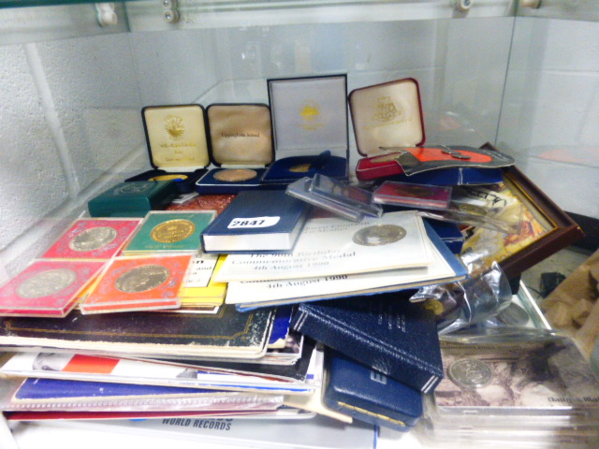 Large shelf of mixed collectable coins in presentation cases