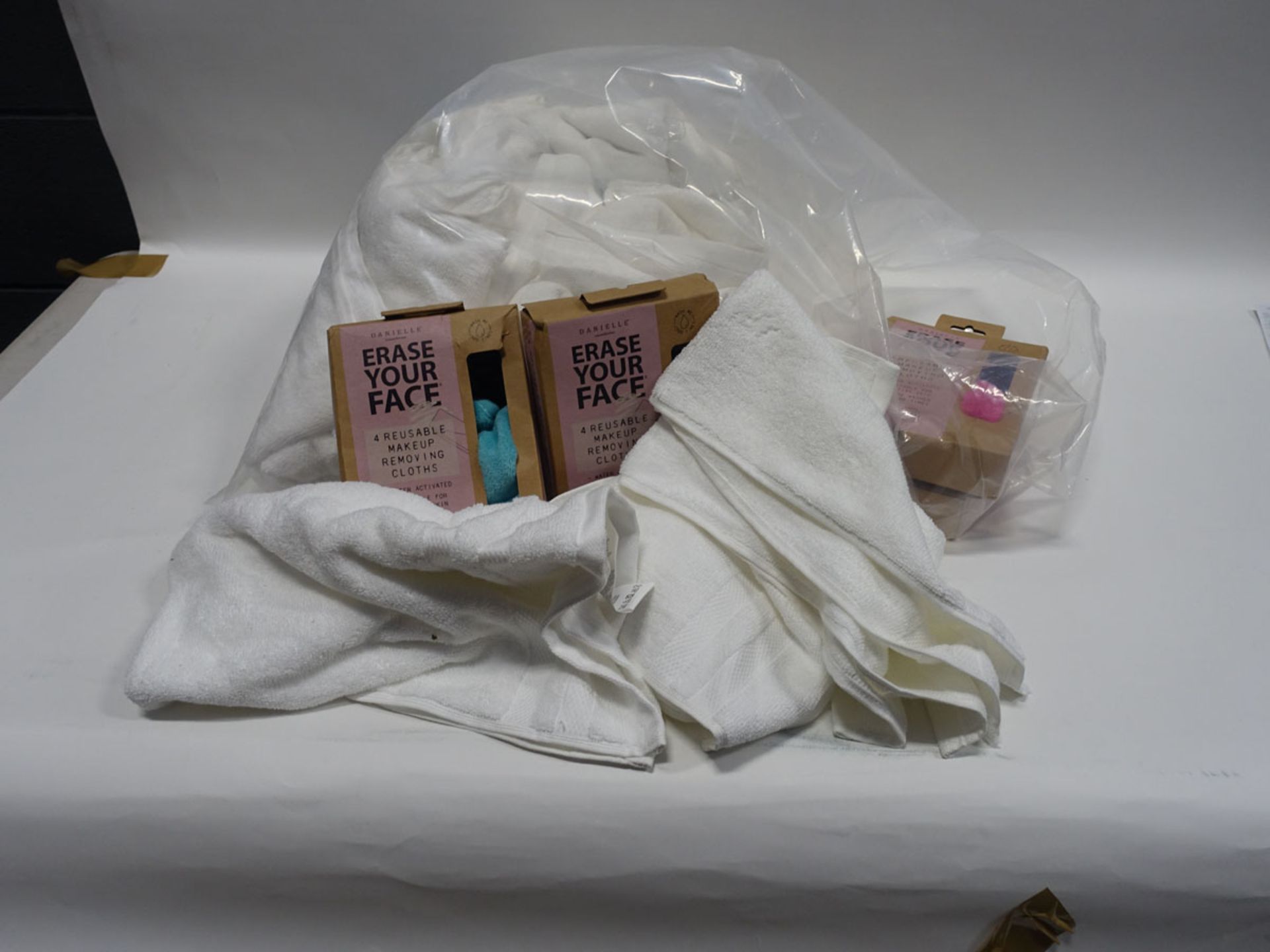 Bag of white hand towels together with a small quantity of Erase Your Face re-usable make-up