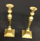 A pair of square based antique brass candlesticks