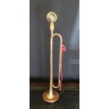 A table lamp made from a vintage Fanfare Bugle on an oak base plinth