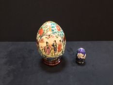 An antique moriage handpainted porcelain egg and a small closionne enamel on stand