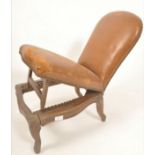A 19th century oak and leather gout stool in the form of a French fauteuil.