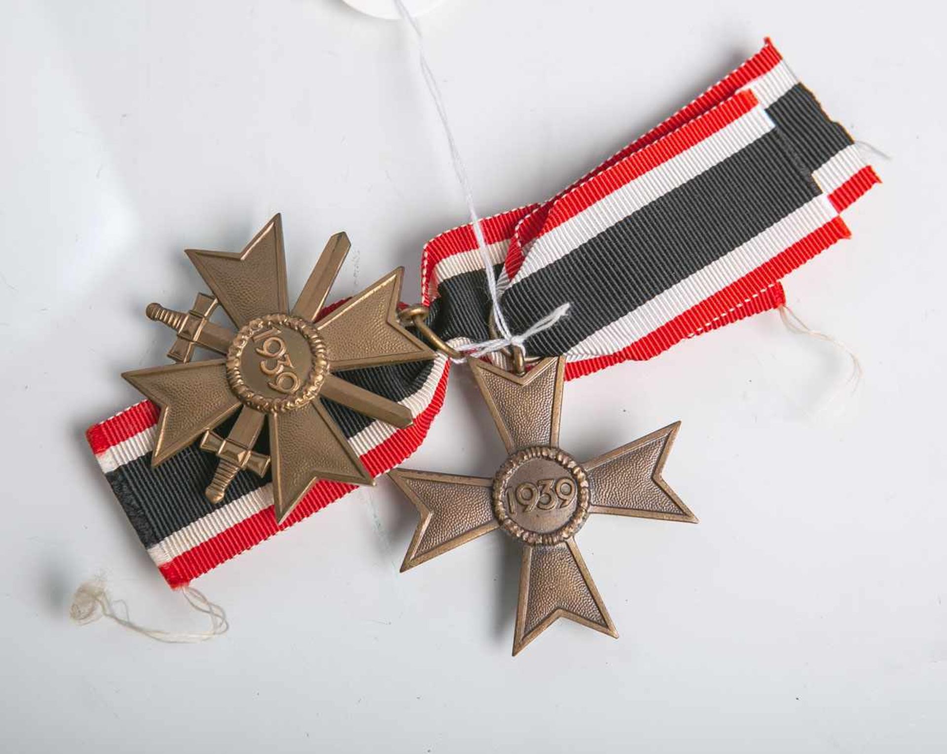 Zwei Kriegsverdienstkreuze (Drittes Reich, 1939), aus Buntmetall mit Bandabschluss,
