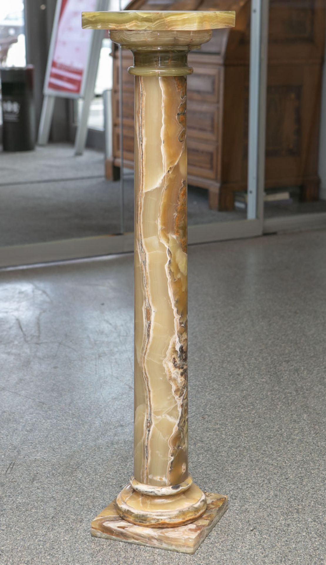 Onyx-Säule, grün-hellbraun marmoriert, H. ca. 101 cm, Dm. Platte ca. 21,5 x 21,5 cm.