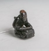 Tropenholz-Netsuke (Provenienz Japan, Alter unbekannt), Shoki, der auf einem Stein seinSchwert