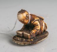 Elfenbein-Netsuke (Provenienz Japan, Alter unbekannt), knieender Knabe, der zweiSchachteln