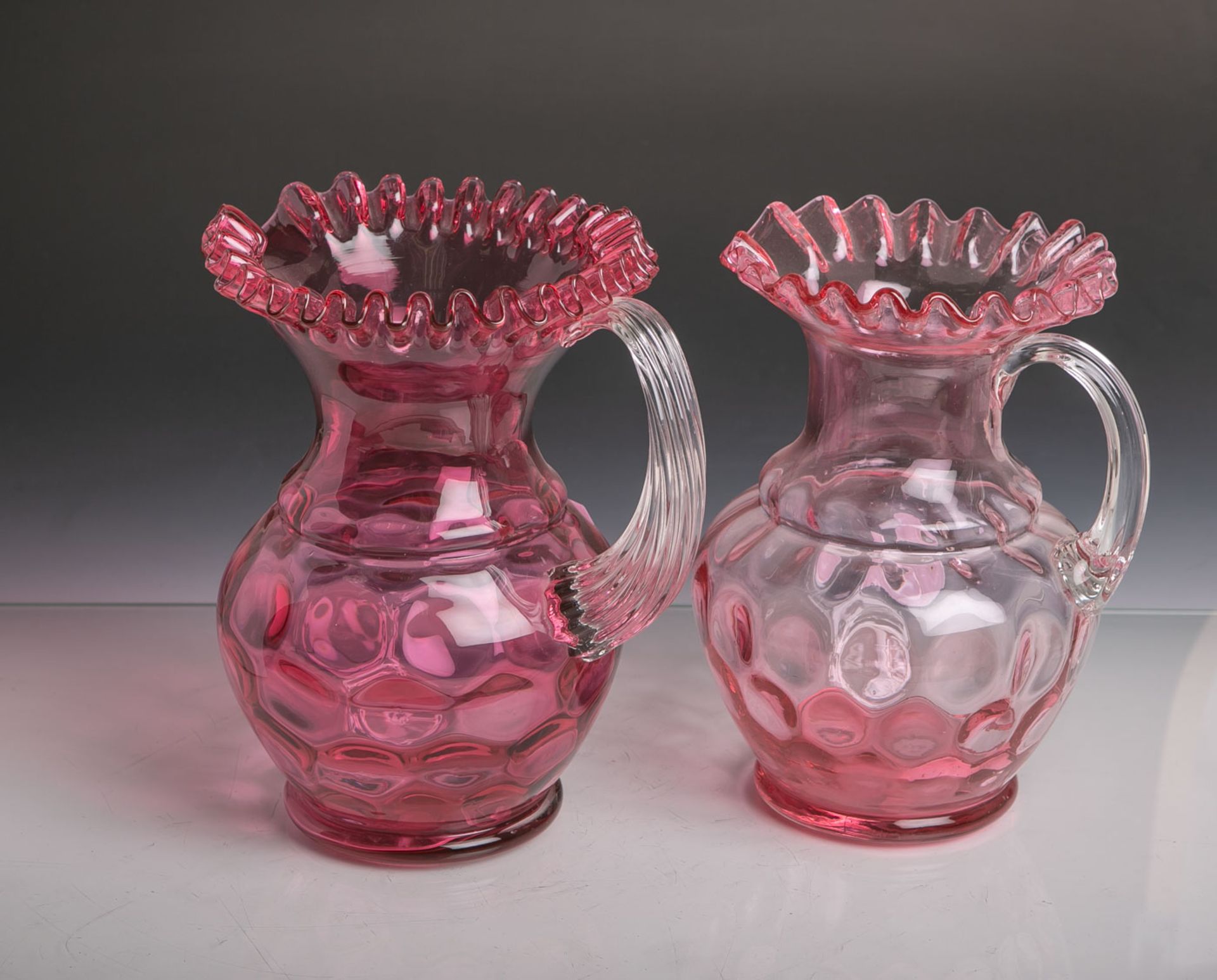 2 Roseglas-Karaffen (um 1890/1900), je m. Reliefdekor, H. je ca. 25 cm. KeineBeschädigungen