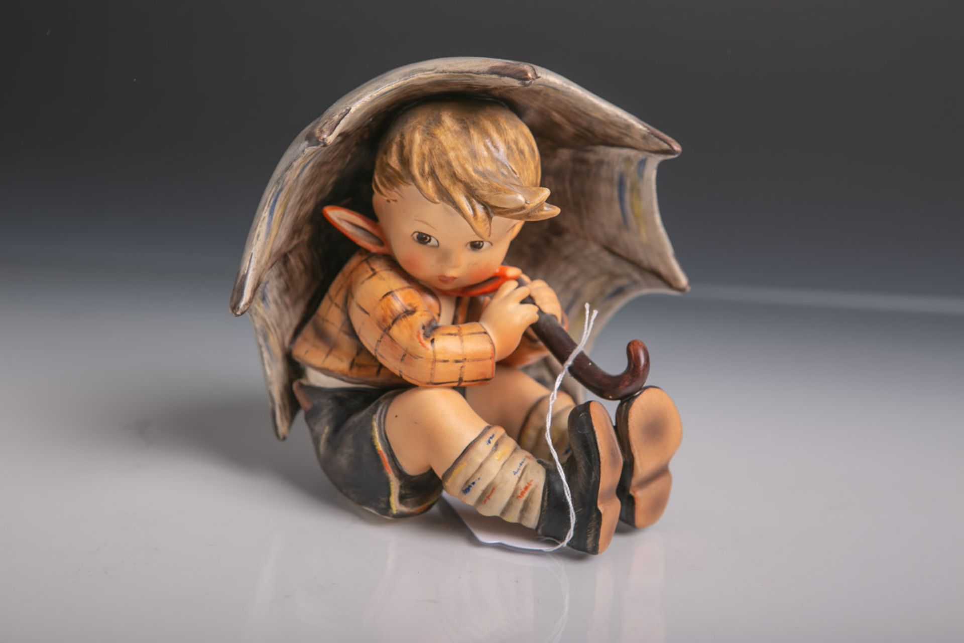 Knabenfigur unter einem großen Schirm sitzend (Hummel) aus Keramik/Porzellan von Goebel