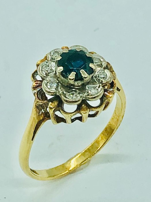 An 18ct yellow gold ring, centre claw set 5mm round sapphire with eight illusion set diamonds.