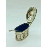 A silver mustard pot with spoon and blue glass liner