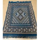 A hand knotted rug from Tunisia, geometric styling in blue, beiges and tan measuring 235cm x 167cm