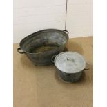 A large galvanised tin bath and a galvanised tin washing bucket with lid