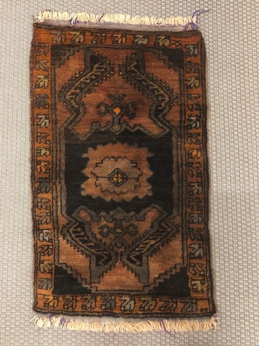 A small black and brown Turkish rug measuring 90cm x 56cm