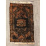 A small black and brown Turkish rug measuring 90cm x 56cm