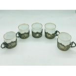 A set of five porcelain coffee cans with hallmarked silver holders (one without a handle)