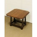 A small oak table with hinged top that rotates to open on turned legs with stretchers (59cm x