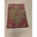 A Persian, red and green pattern rug with tassel to both ends (148cm x 100cm) from the Estate of