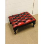 A red leather button ottoman with brass stud edging on cabriole legs (W65cm D50cm H30cm)