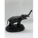 A bronze of an elephant on a marble plinth.