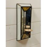 A contemporary mirrored wall hanging candle holder