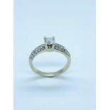 A modern solitaire diamond ring with diamond shoulders in 18 ct white gold setting. Central