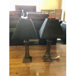 A pair of bonze coloured table lamps with black shades with bronze interior and leaf pattern
