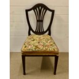 An oak hall chair with shield shaped back and inwardly curved splats with a needlework upholstered