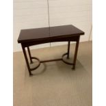 A mahogany card table with hinged swivel top and stretcher to base