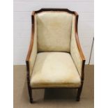 An Edwardian style wooden framed upholstered chair with down swept arms and tapered legs