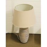 A table lamp with a cream pottery base with wood effect stripes and linen shade standing 63cm tall