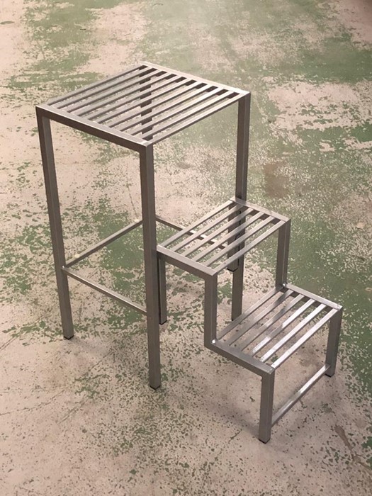 A silver coloured metal stool with steps